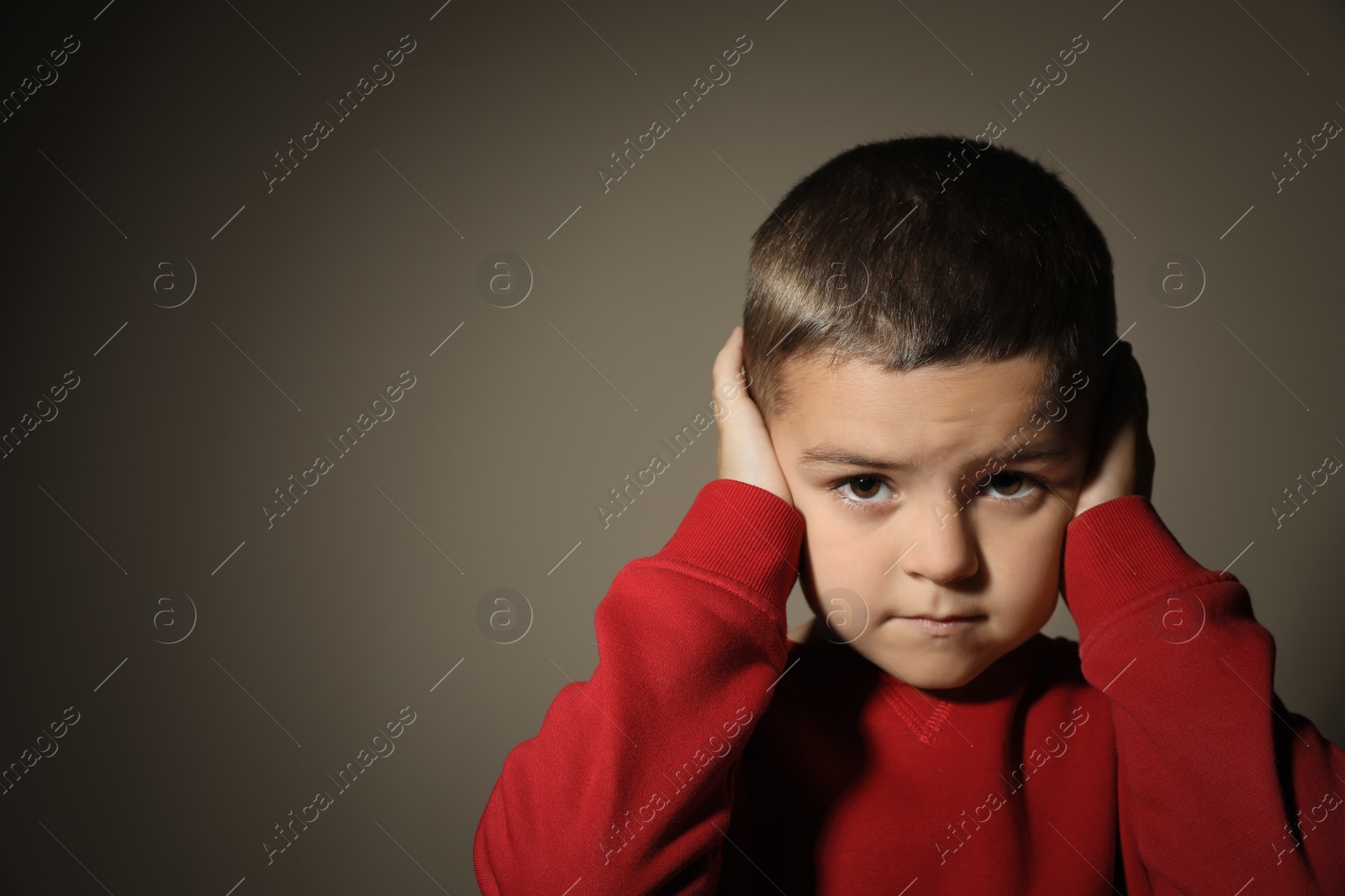 Photo of Scared little boy on beige background, space for text. Domestic violence concept