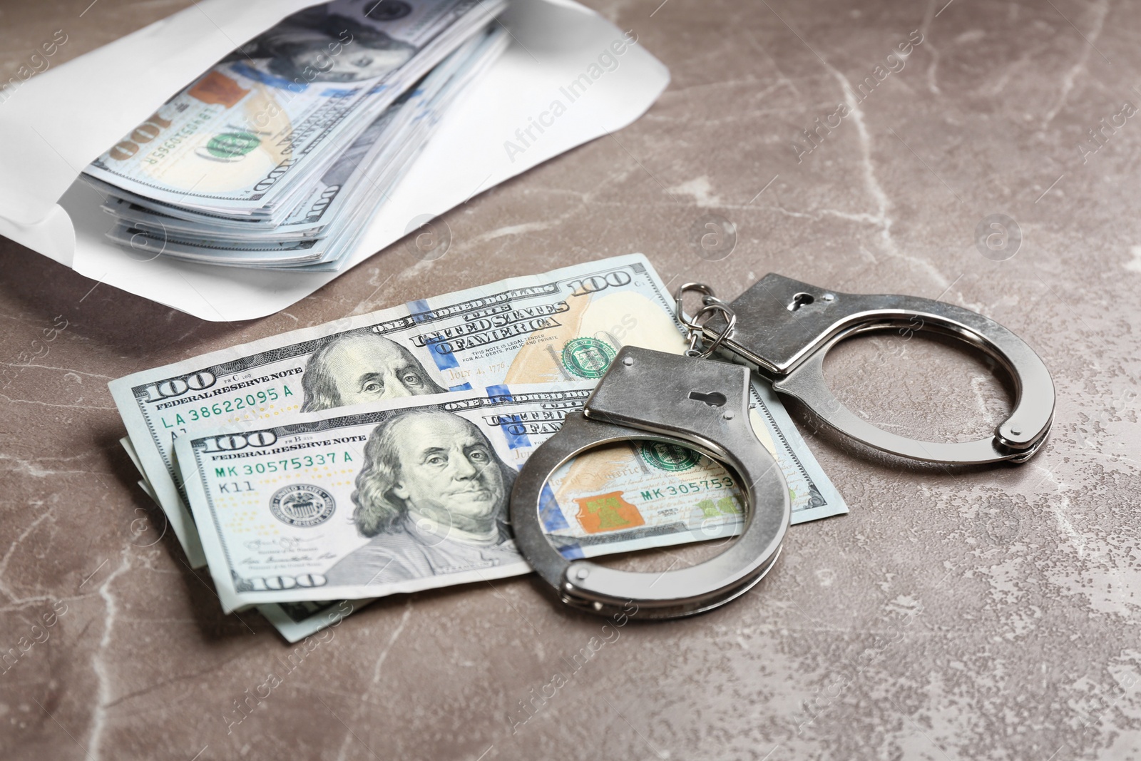 Photo of Dollar bills and handcuffs on brown marble table. Bribe concept