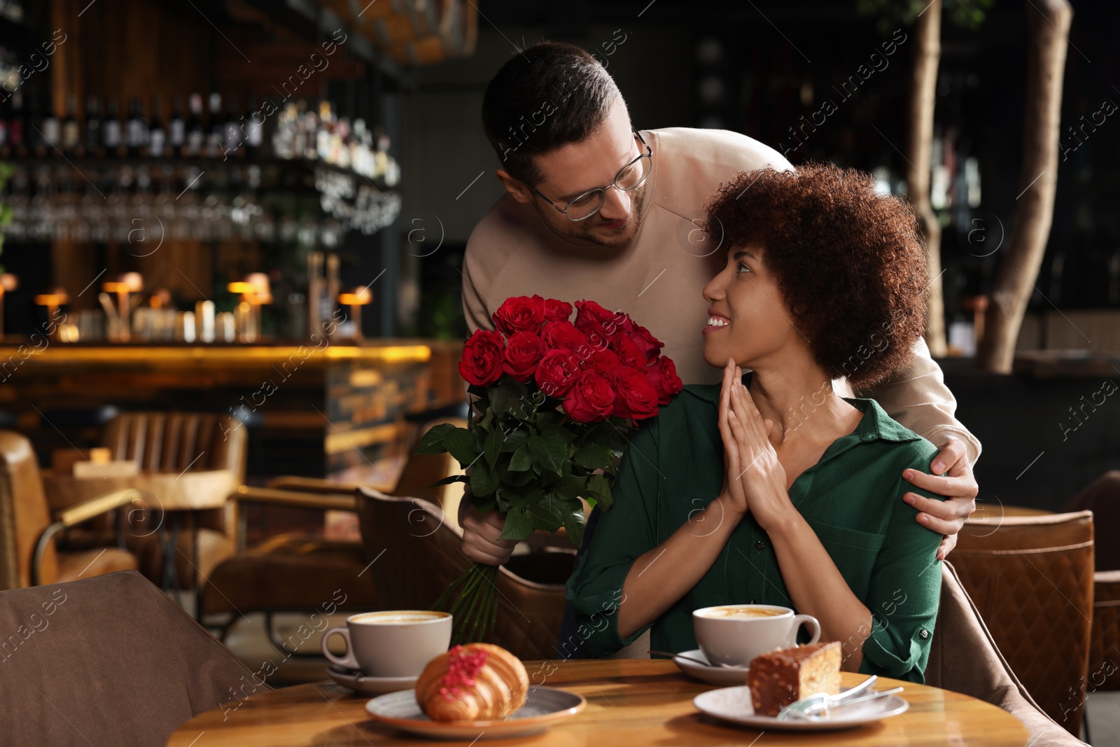Photo of International dating. Handsome man presenting roses to his girlfriend in restaurant, space for text
