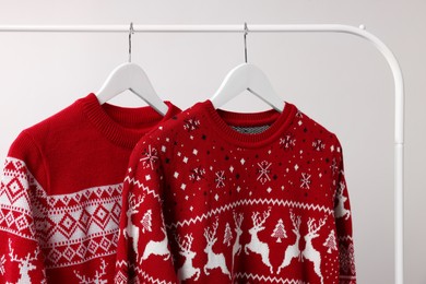 Photo of Rack with Christmas sweaters on light background