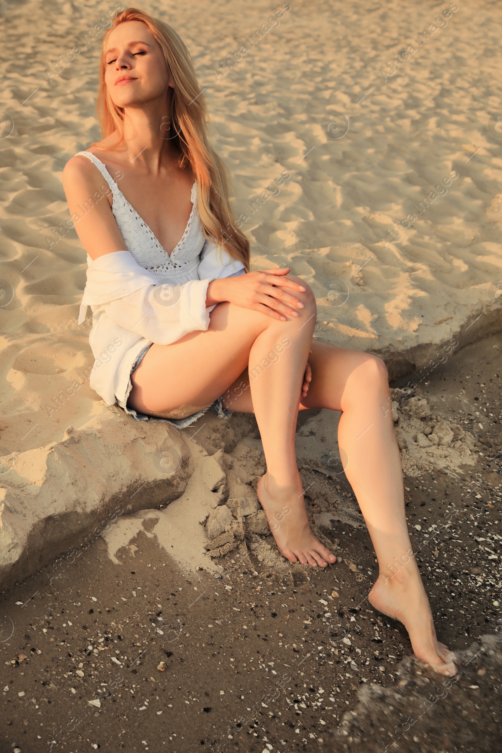 Photo of Beautiful young woman sitting on sandy beach