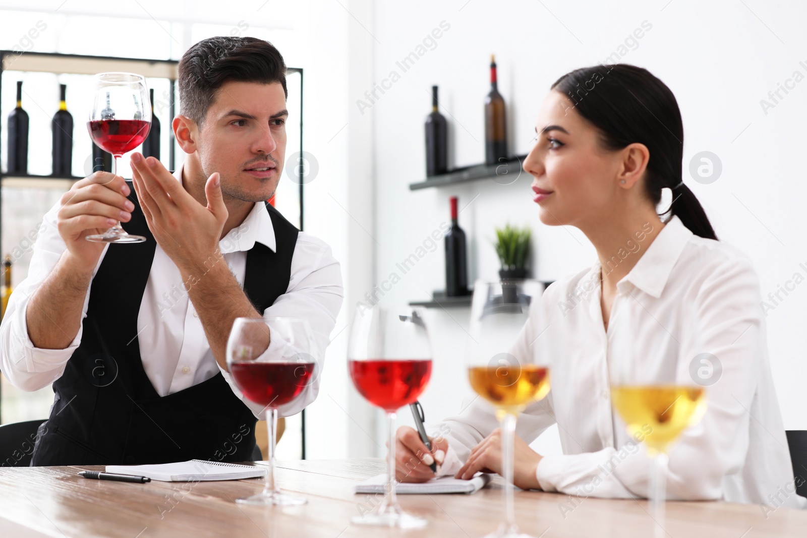 Photo of Sommeliers tasting different sorts of wine at table indoors