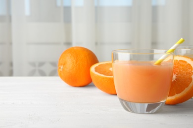 Photo of Glass with orange juice and fresh fruit on table, space for text