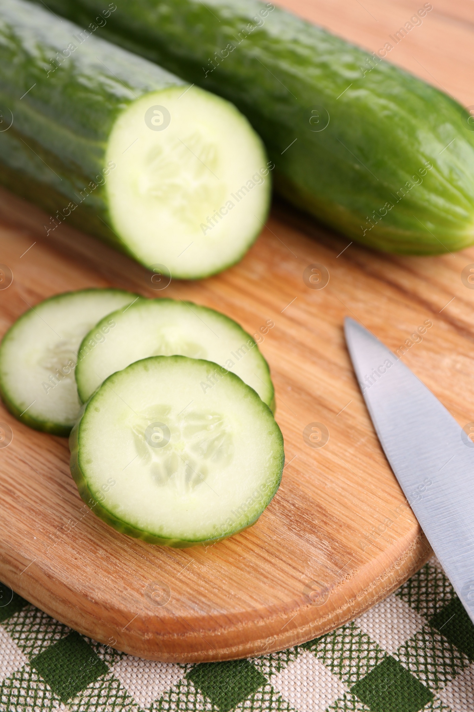 Photo of Cucumbers, knife and cutting board on table, closeup