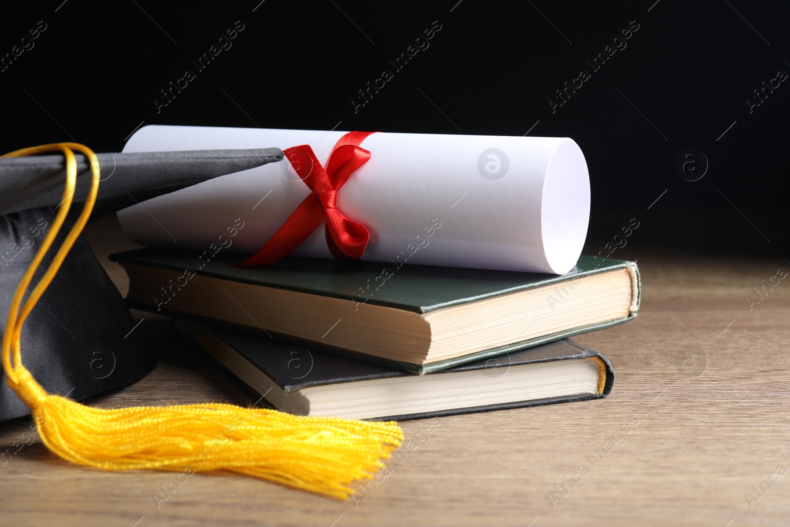 Photo of Graduation hat, books and student's diploma on wooden table