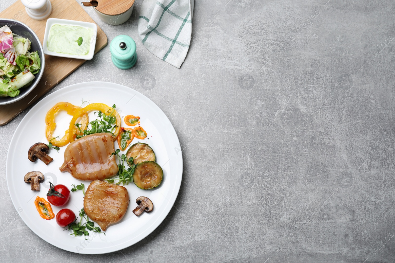 Photo of Delicious grilled squid tubes served on grey table, flat lay. Space for text