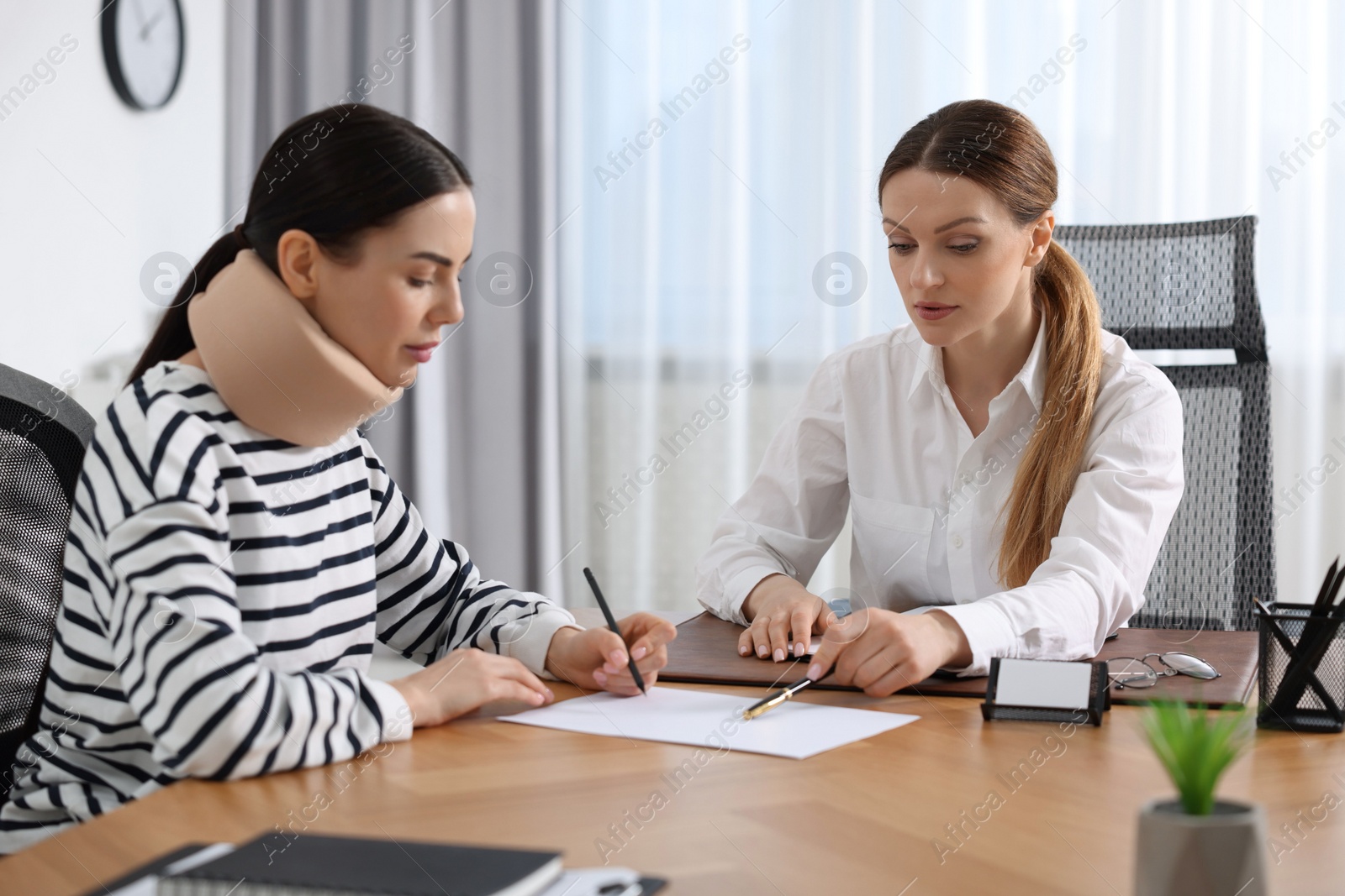 Photo of Injured woman signing document in lawyer's office