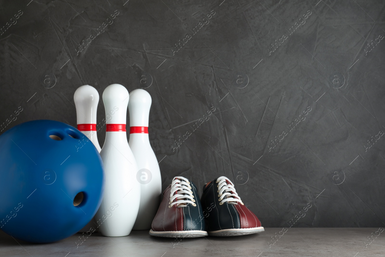 Photo of Bowling shoes and ball on grey stone table. Space for text