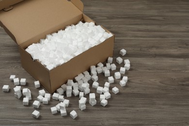 Cardboard box and styrofoam cubes on wooden floor. Space for text