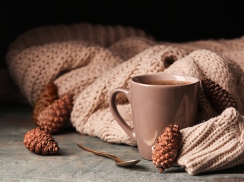 Photo of Composition with cup of hot cozy drink and autumn sweater on table. Space for text