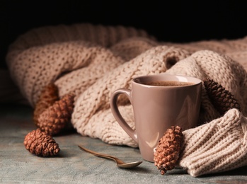 Composition with cup of hot cozy drink and autumn sweater on table. Space for text