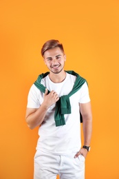 Young man with trendy hairstyle on color background