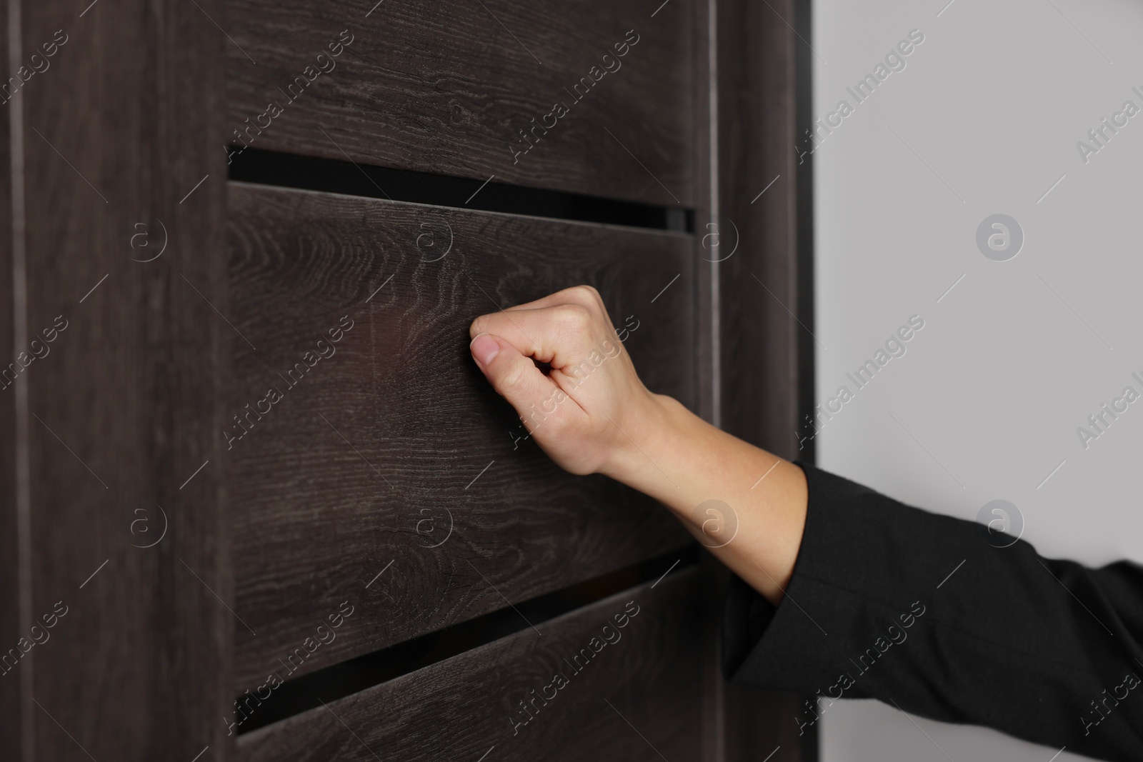 Photo of Collector knocking on door indoors, closeup view