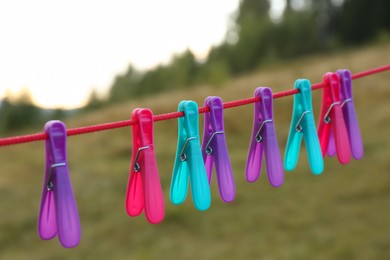 Photo of Colorful clothespins hanging on washing line outdoors