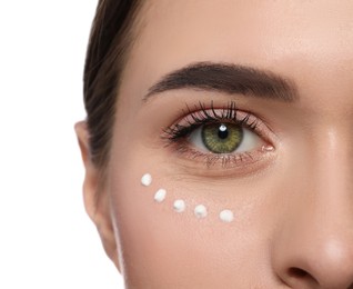 Young woman with cream around eye on white background, closeup