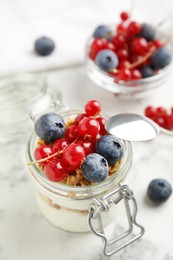 Delicious yogurt parfait with fresh berries on white marble table, closeup