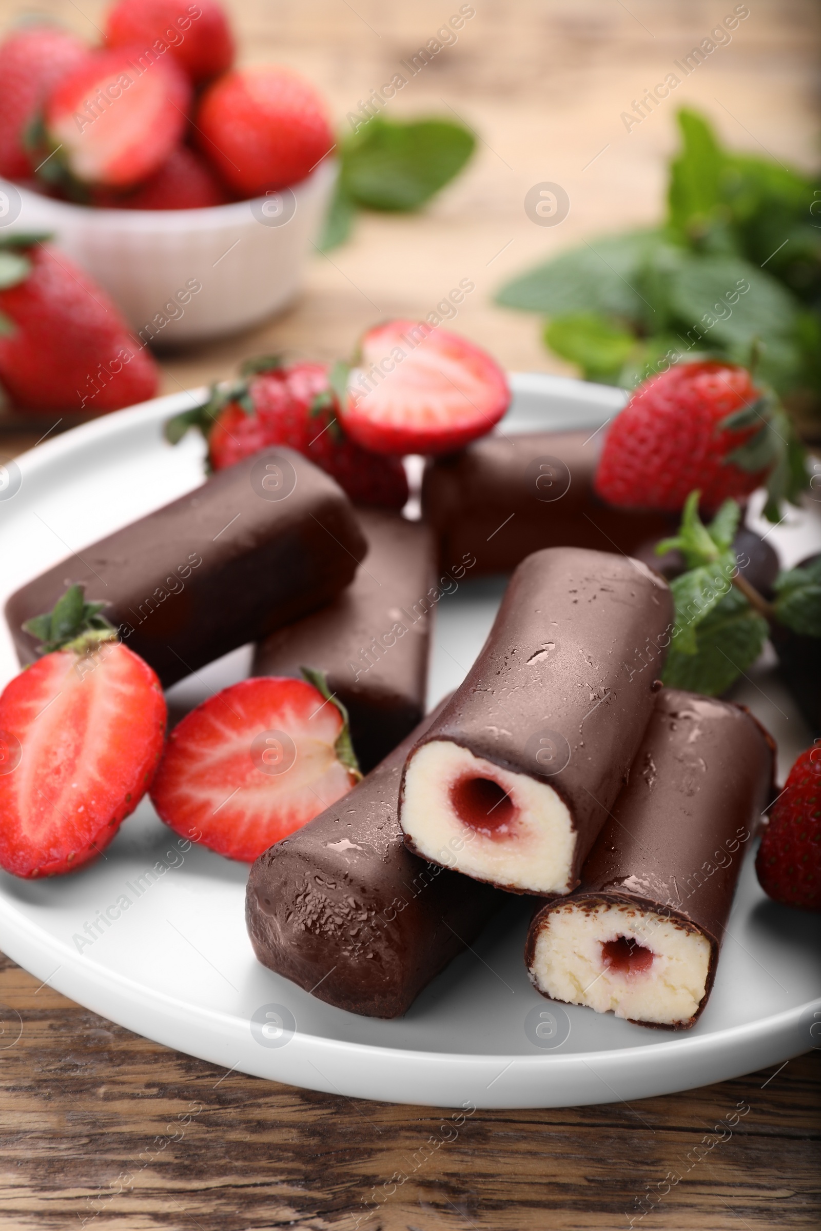 Photo of Delicious glazed curd snacks with fresh strawberries and mint on wooden table