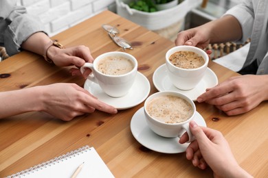 Women with cups of coffee at table in cafe, closeup