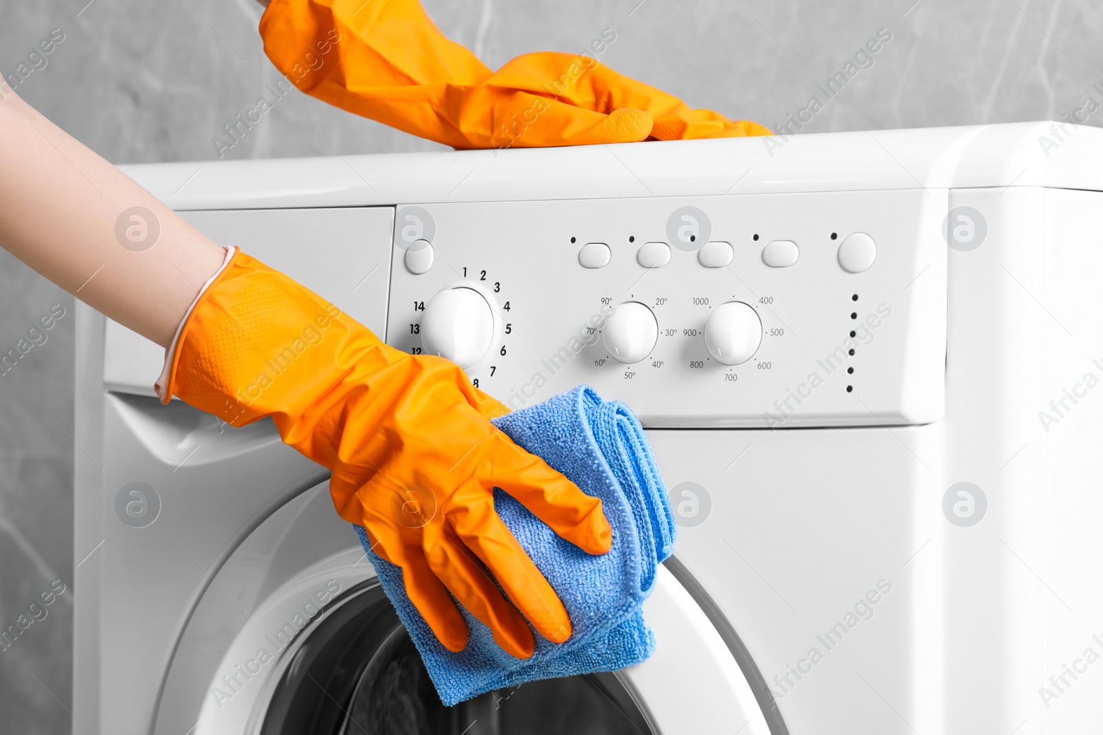 Photo of Woman cleaning washing machine with rag indoors, closeup