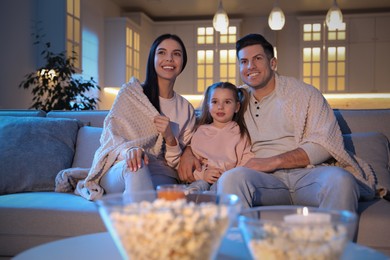 Photo of Family watching movie on sofa at night