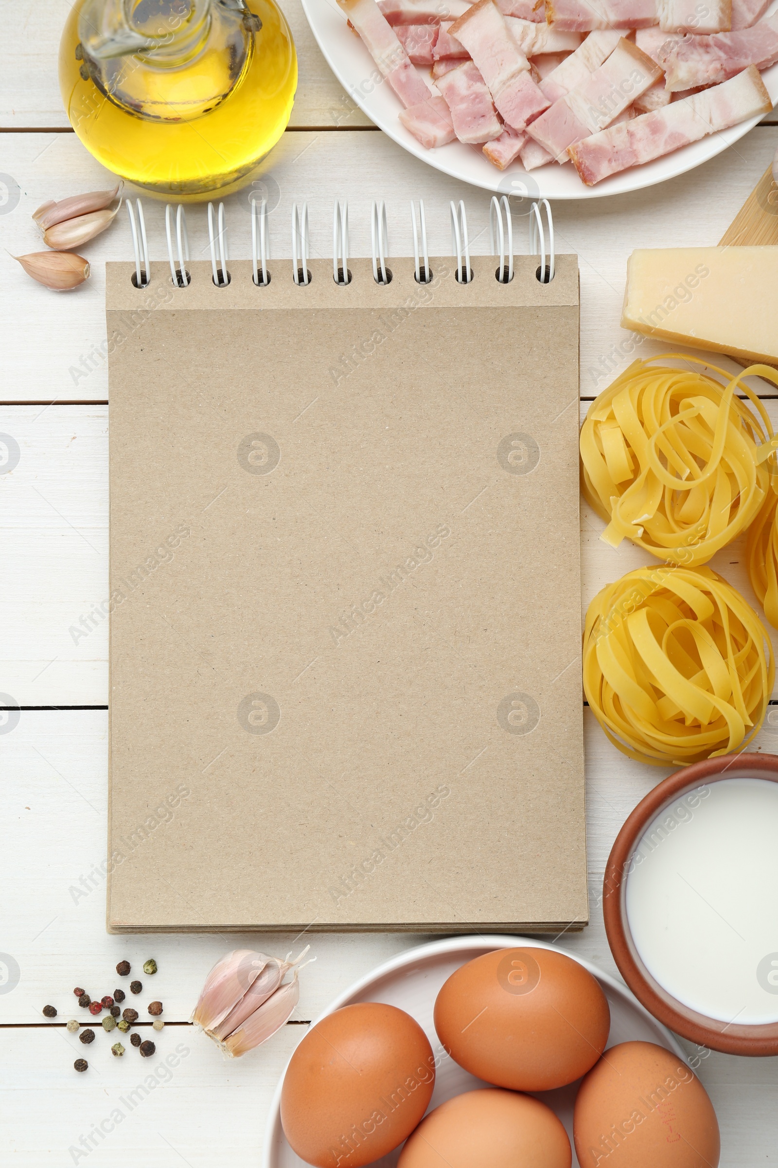 Photo of Blank recipe book and different ingredients on white wooden table, flat lay. Space for text