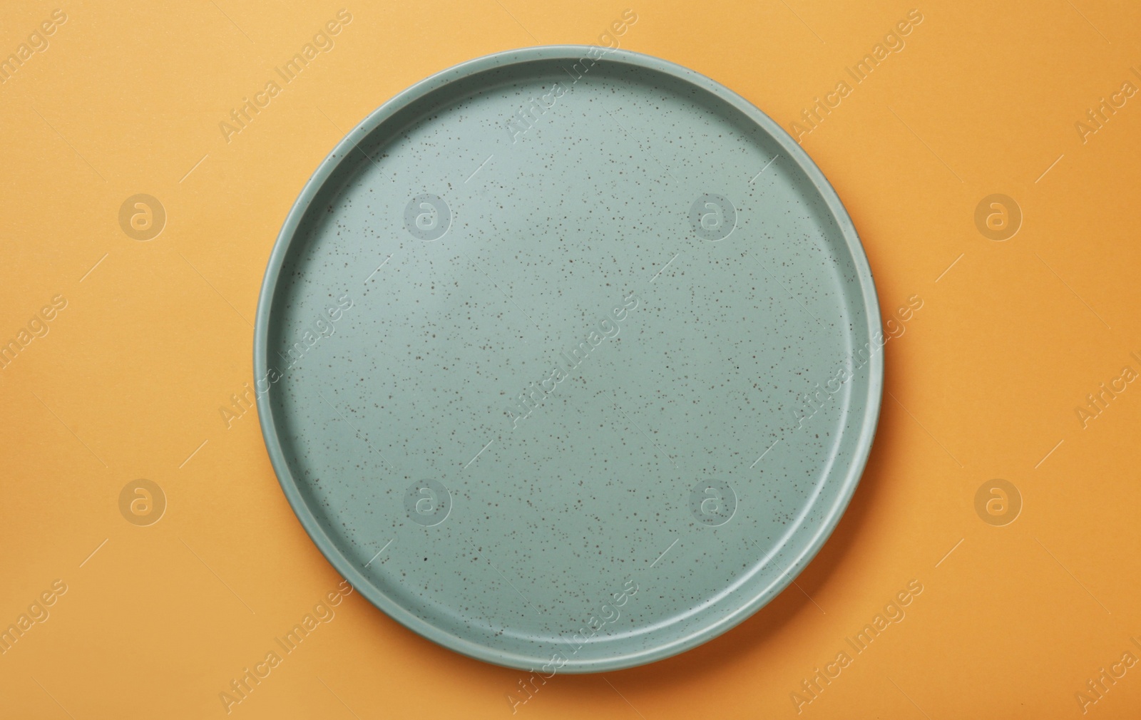 Photo of Empty ceramic plate on pale orange background, top view