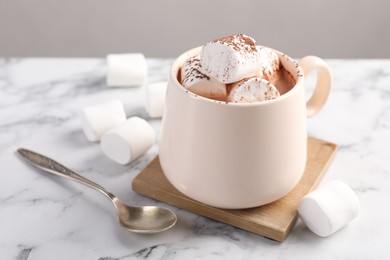 Photo of Cup of aromatic hot chocolate with marshmallows and cocoa powder served on white marble table