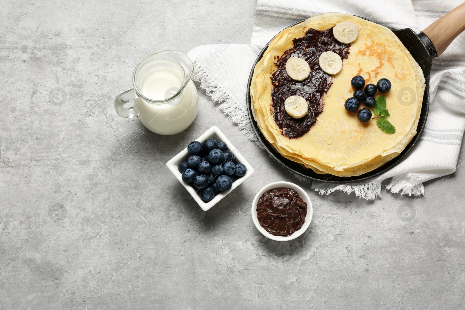 Photo of Delicious crepes with different products on light grey table, flat lay. Space for text