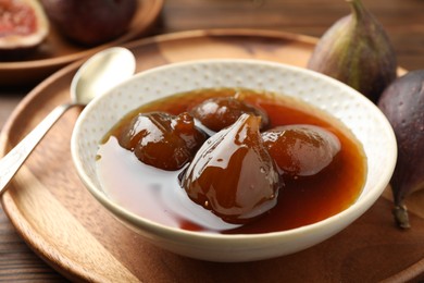 Photo of Bowl of tasty sweet jam and fresh figs on wooden table, closeup