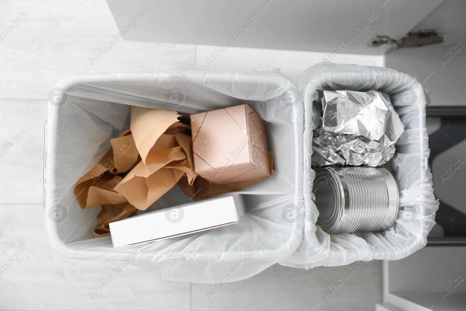 Photo of Open cabinet with full trash bins for separate waste collection in kitchen, top view