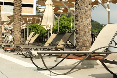 Photo of Sunbeds near swimming pool at luxury resort