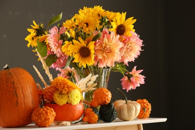 Photo of Autumn composition with beautiful flowers and pumpkins on white table against dark grey background