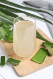 Photo of Fresh aloe juice in glass and leaves on white wooden table, closeup