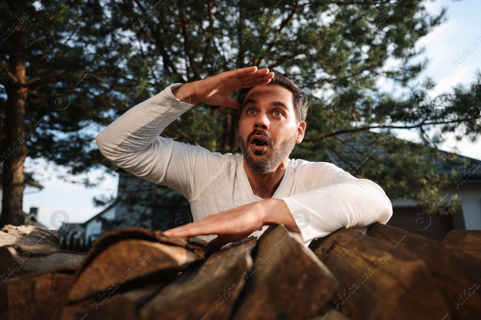 Photo of Concept of private life. Curious man spying on neighbours over firewood outdoors, low angle view