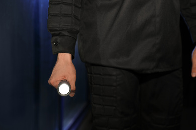 Photo of Male security guard with flashlight in dark room, closeup