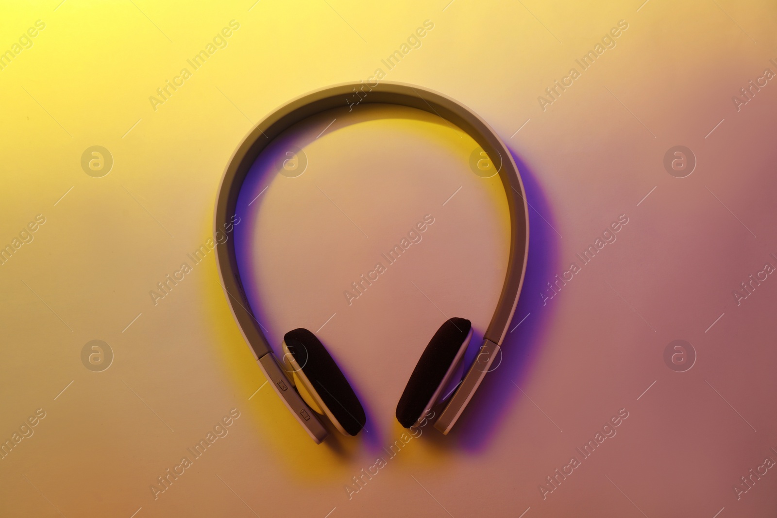 Photo of Stylish modern headphones with earmuffs on color background, top view