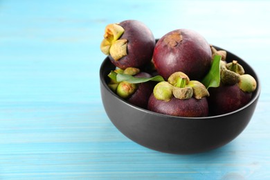 Photo of Fresh ripe mangosteen fruits on light blue wooden table. Space for text