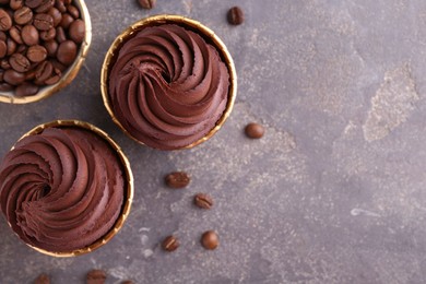 Delicious chocolate cupcakes and coffee beans on grey textured table, flat lay. Space for text