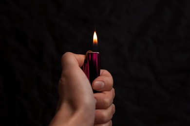 Woman holding lighter on black background, closeup