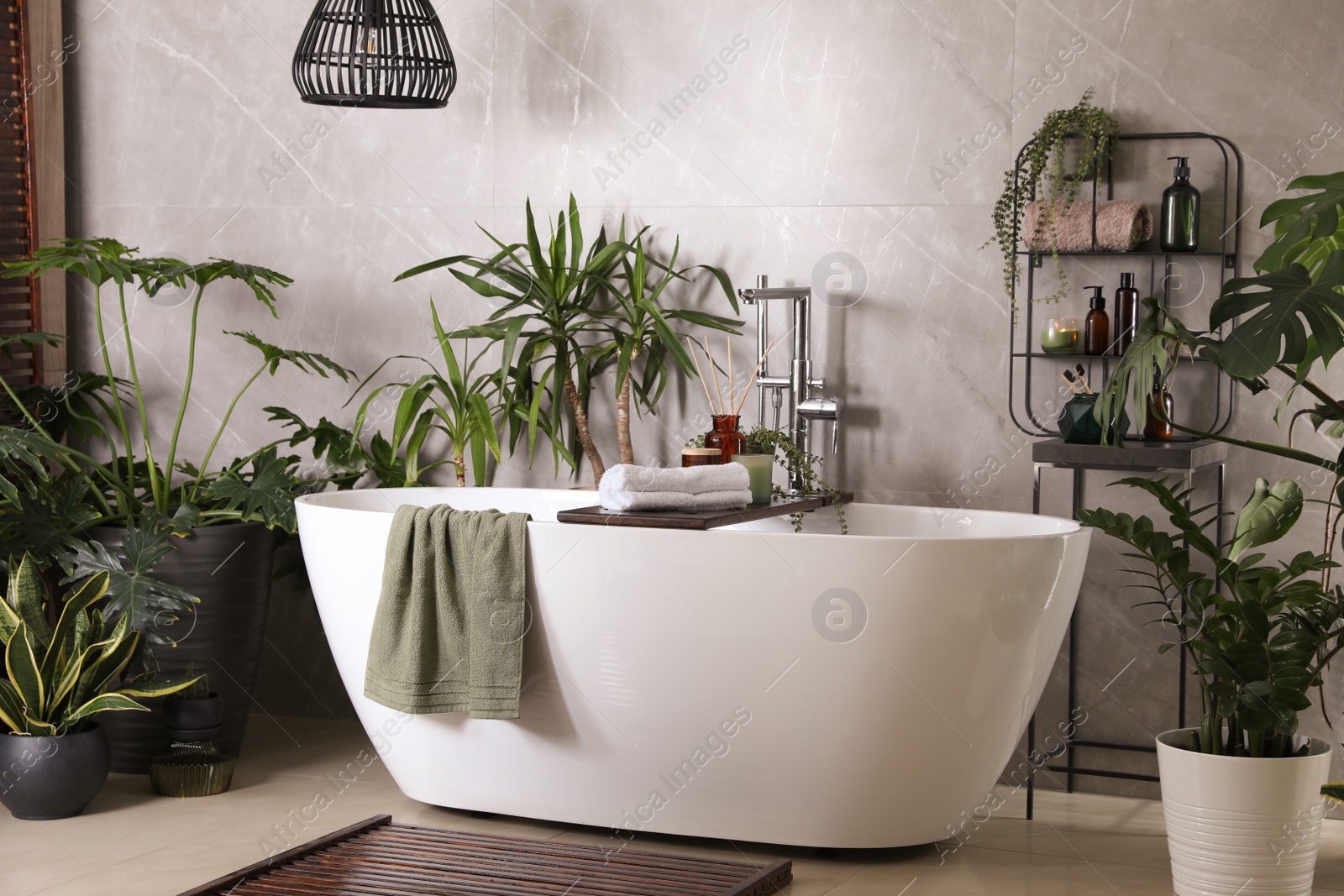 Photo of Modern white tub and beautiful green houseplants in bathroom. Interior design