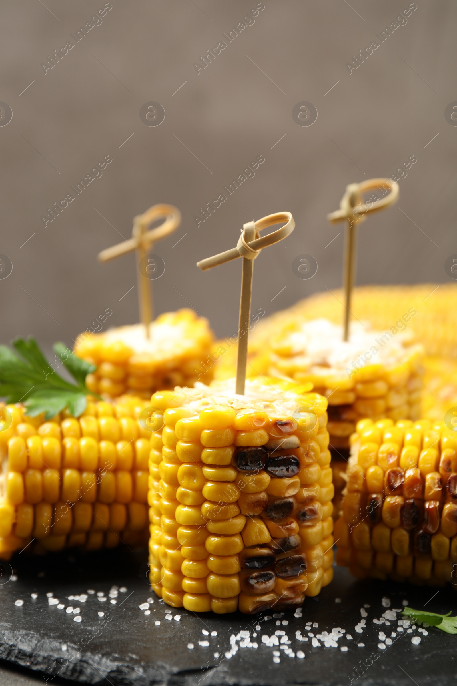 Photo of Tasty grilled corn on black plate, closeup view