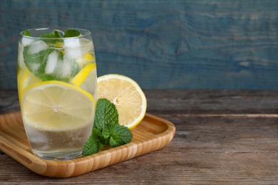 Photo of Delicious lemonade made with soda water and fresh ingredients on wooden table. Space for text