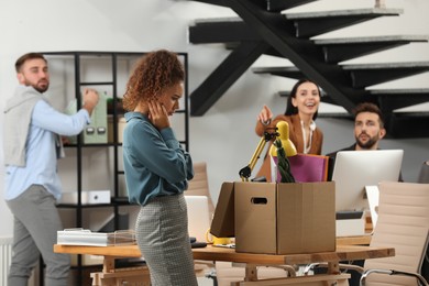 Young dismissed woman near box with stuff at office