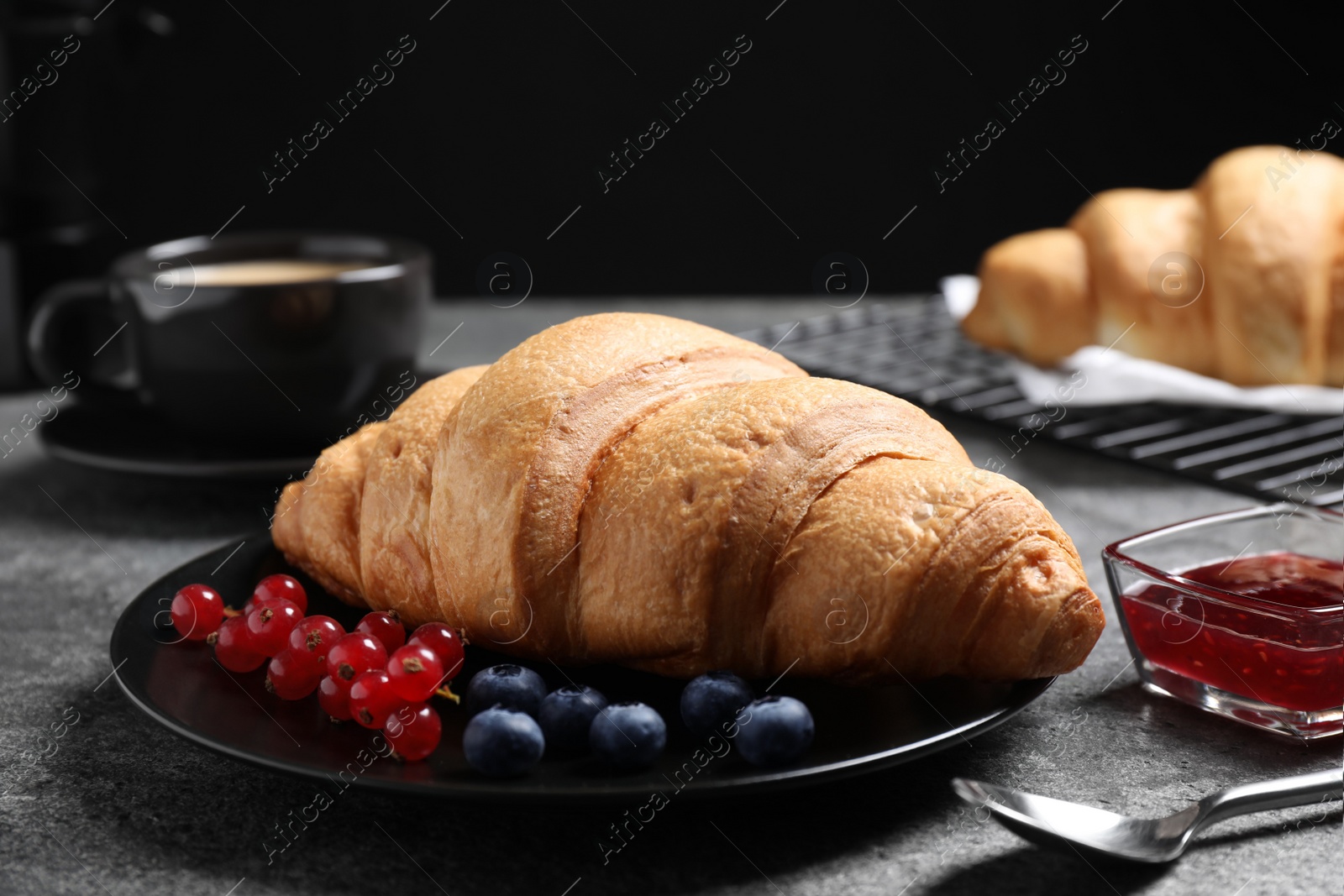 Photo of Plate with fresh crispy croissant and berries on grey table