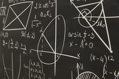 Different mathematical formulas written with chalk on blackboard