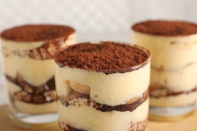 Delicious tiramisu in glasses on blurred background, closeup