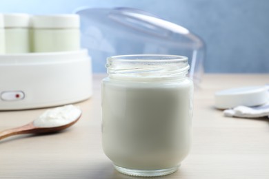 Glass jar with tasty yogurt on white wooden table