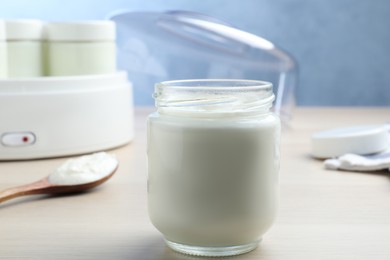 Photo of Glass jar with tasty yogurt on white wooden table