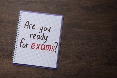 Photo of Notebook with question Are You Ready For Exams? on wooden table, top view. Space for text