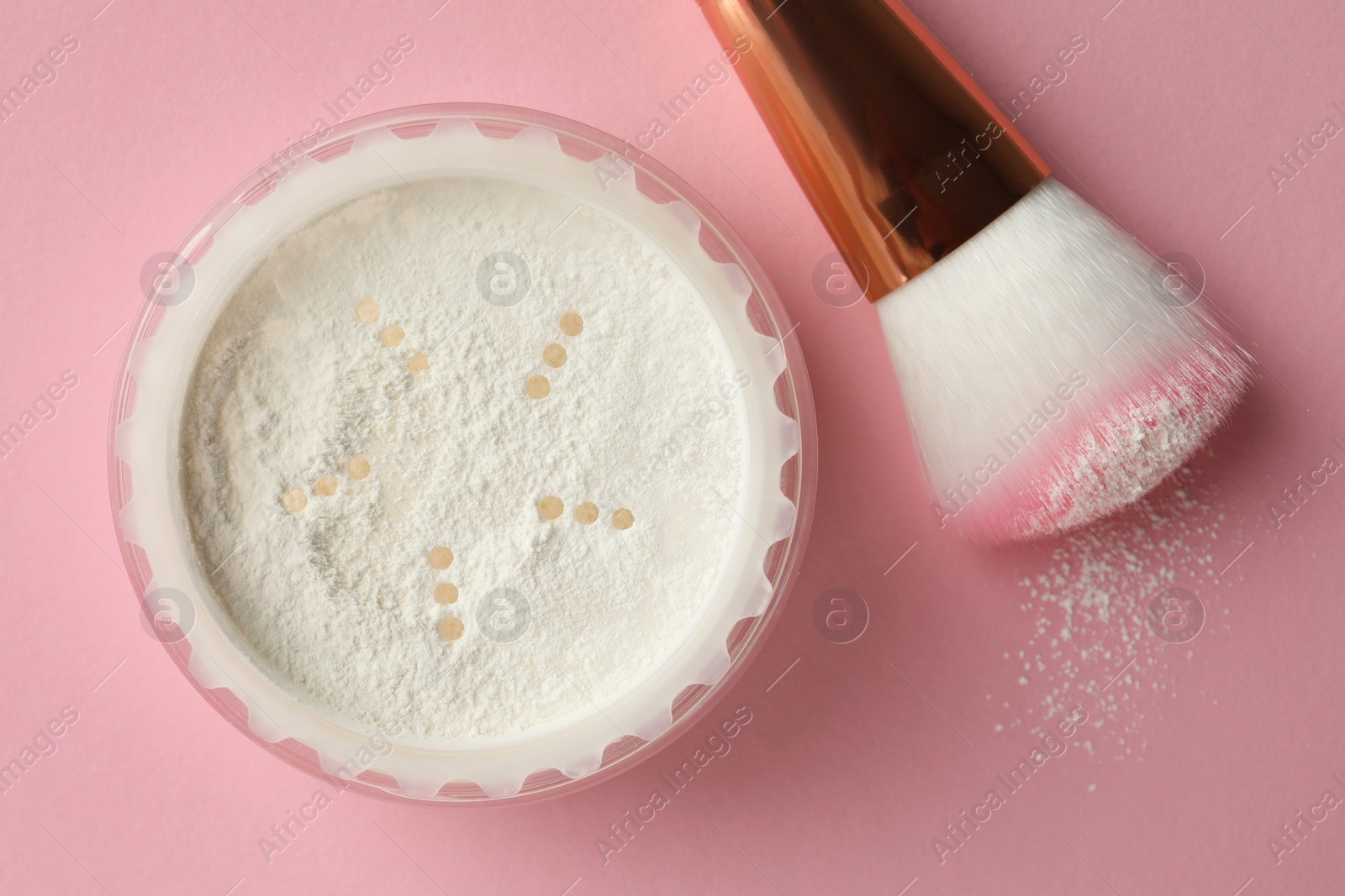 Photo of Rice loose face powder and makeup brush on pink background, flat lay